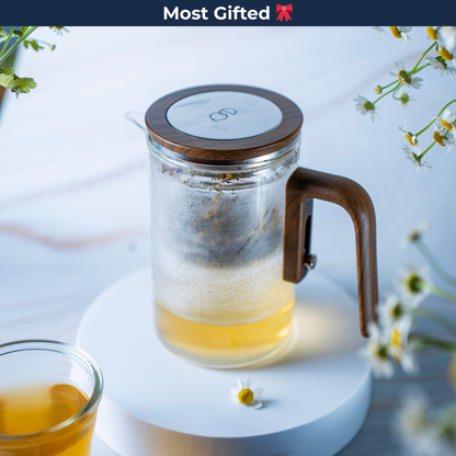 EQ Tea Steeper on a circular stand with flowers and a teacup in the background